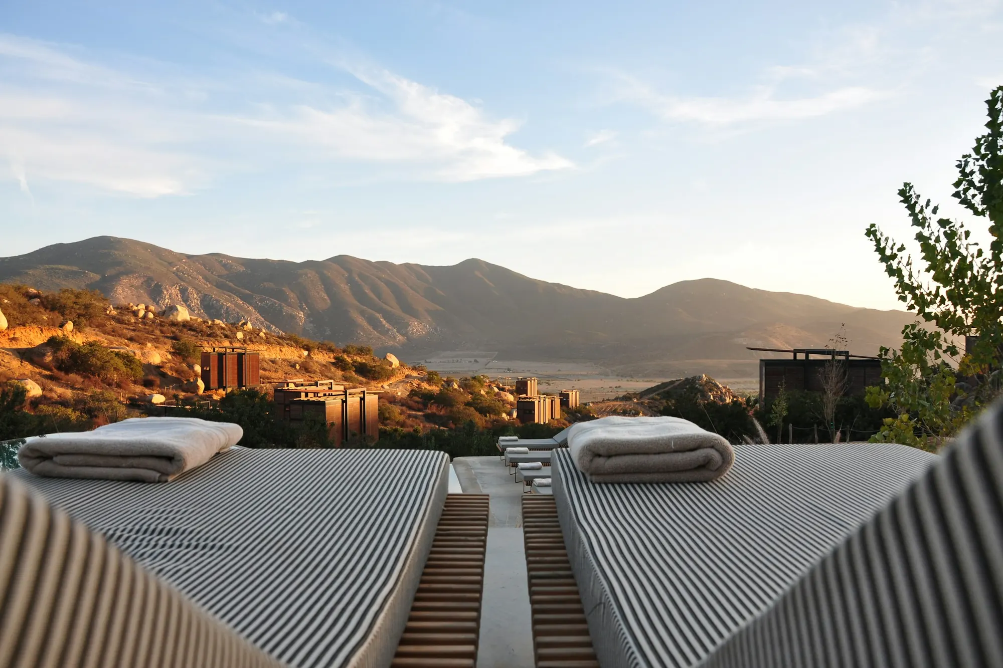 Sun loungers on a terrace facing a mountain range in late light